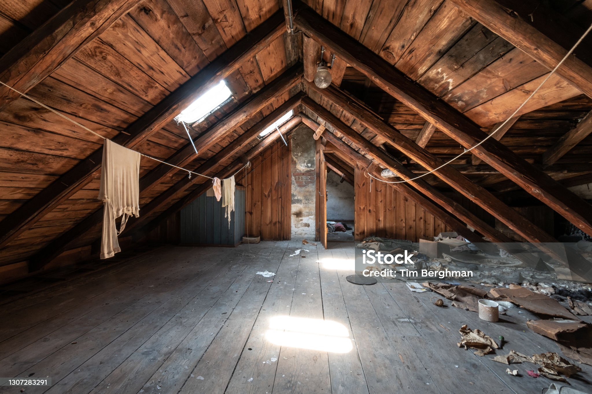 Attic room with clothesline, wooden trim and junk on the floor